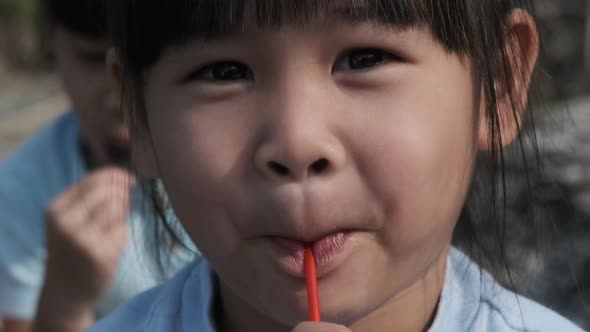 Cute little girl eating lollipops. Happy little Asian girl enjoys eating lollipops.