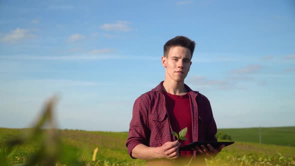 Farmer with Tablet Looking at Camera on Soybean Field