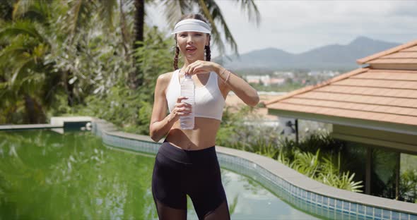 Slim Sportswoman Drinking Water Near Swimming Pool