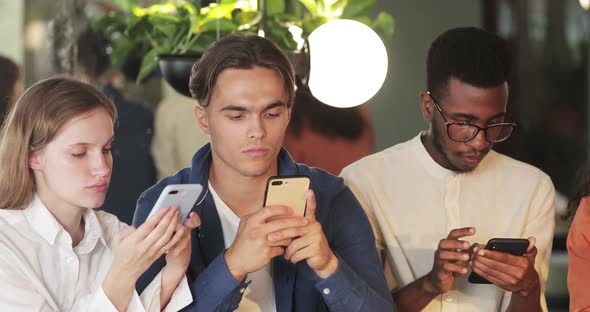 Close Up View of Young Concentrated People Phubbing Smartphones While Spending Time Together