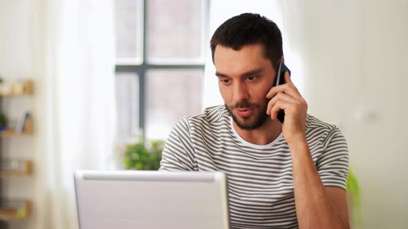 Man with Laptop Calling on Phone at Home Office