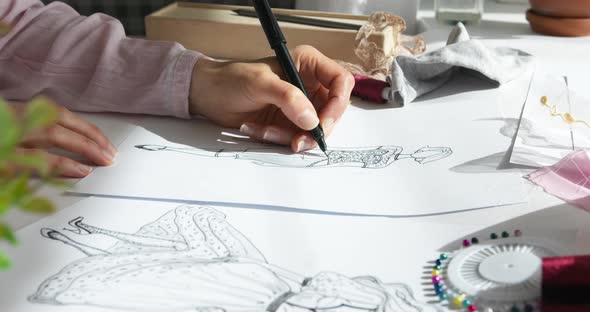 The designer of women's clothing dresses is drawing a sketch on paper. 4K