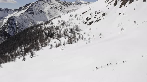 Winter Aerial Over Group of People with Snowshoes Hiking Down a Snowy Slope