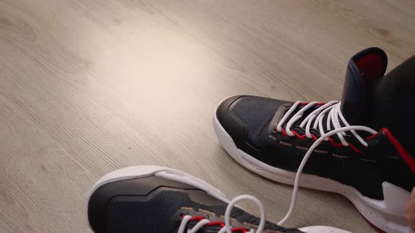 Closeup of a Man Wearing a Black Sock Basketball Sneaker on His Foot and Tying His Shoelace