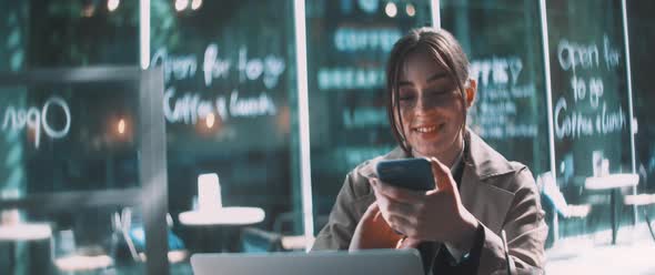 Young business woman looking up and smiling while working on laptop at a cafe