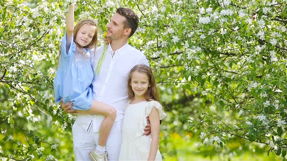 Happy Family in Blooming Garden on Beautiful Spring Day
