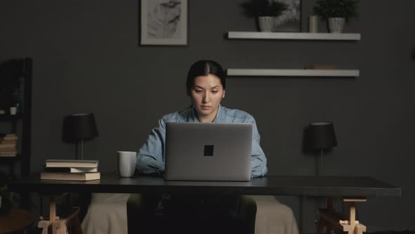 Thoughtful concerned asian woman working on laptop computer at home office, serious woman 