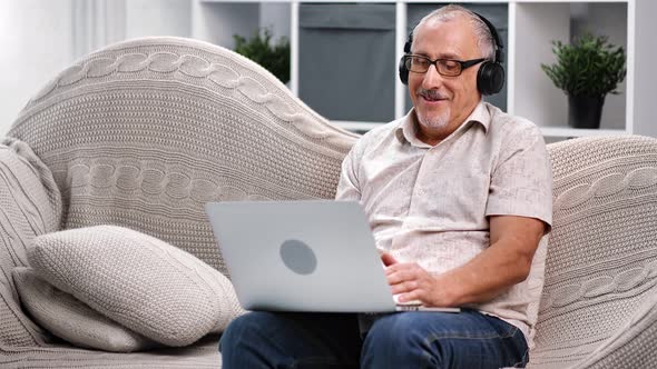 Happy Senior 70s Grandfather User Talking Video Call Online Use Laptop