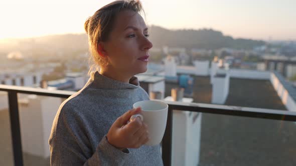 Woman Starts Her Day with a Cup of Tea or Coffee on the Balcony at Dawn Slow Motion