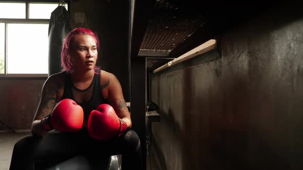 Portrait of athletic young woman in red boxing gloves at the gym