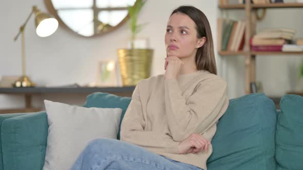 Young Woman Sitting and Thinking on Sofa 