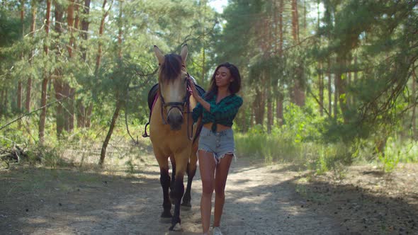 Caring Horsewoman Leading Horse on Forest Trail