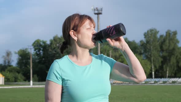 Senior woman drinking water during training