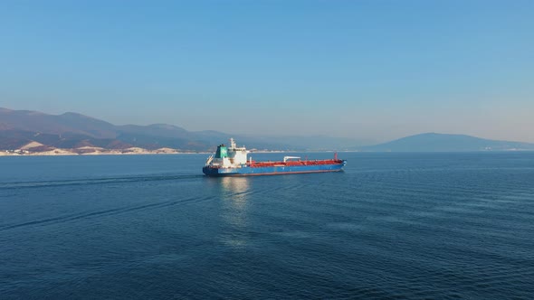 Aerial View of Ultra Large Cargo Ship at Sea Leaves Port at Sunny Day