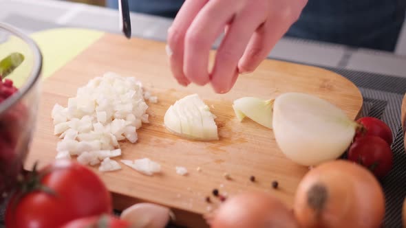 Woman Chopping Onion on Cutting Wooden Board with Sharp Knife