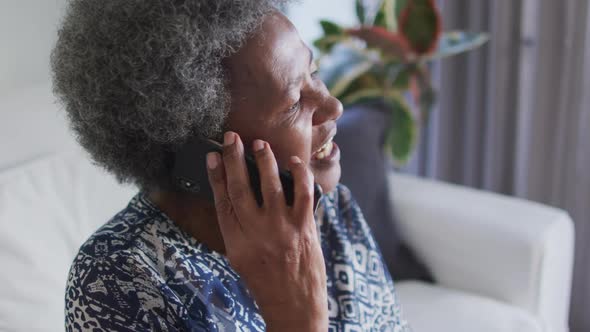 African american senior woman sitting on the couch and using smartphone