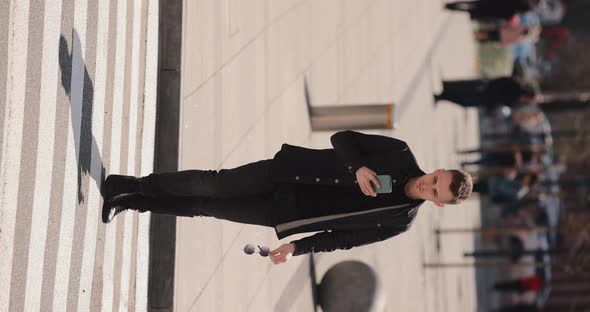 Young Man Using Mobile Phone Crossing the Road on a Zebra Vertical Video