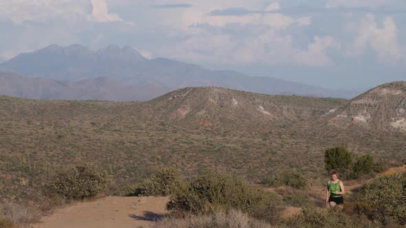 Short-haired woman runs on a trail in the Arizona desert.