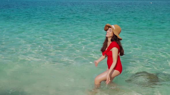 slow-moiton of cheerful young woman walking and playing water splash in the sea beach