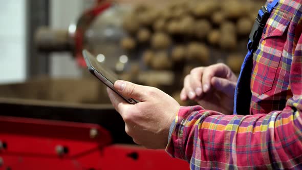 Close-up, Farmer Monitor Quality of Potatoes with Digital Tablet, on Sorting Conveyor Belt in Potato