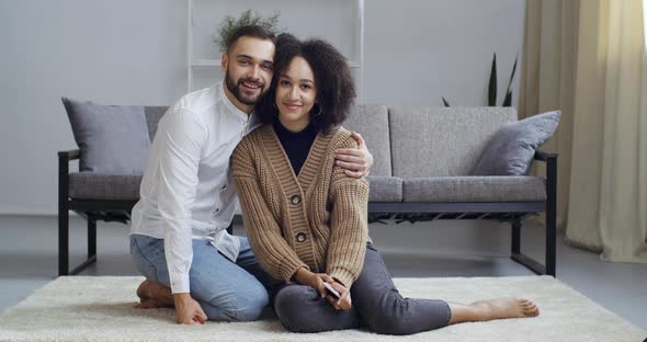 Multiethnic Couple Caucasian Bearded Man and Afro American Woman Hugging on Floor at Home in Living