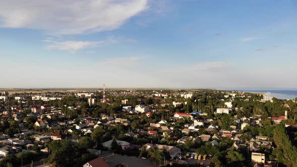 Aerial flyover above the city. Private houses hide between green trees.