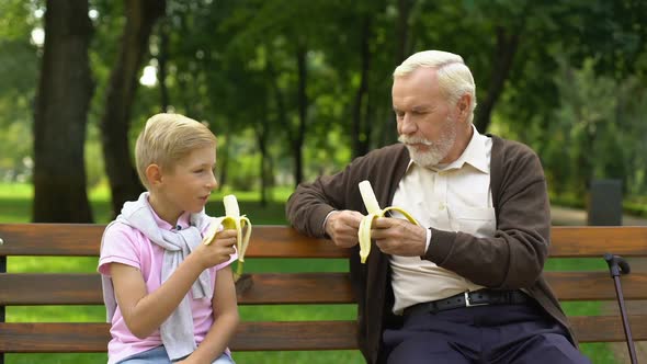 Grandson and Granddad Eating Bananas in Park, Organic Fruits, Healthy Lifestyle