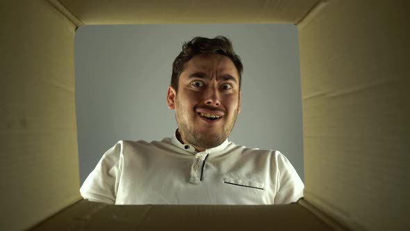 Bottom View Amazed Man Looks Into the Empty Box From the Inside