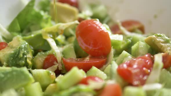 Adding Oil To Tasty Salad with Tomatoes and Avocado in Bowl