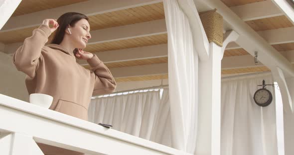 Casual Woman Dancing With The Music Drinking Coffee And Using Smartphone On A Terrace