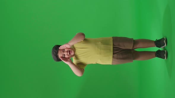 Full Body Of Asian Little Boy Opening His Eyes With Palms In The Green Screen Studio alt