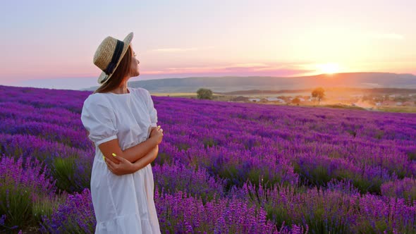 Beautiful Young Woman Wearing White Dress and Hat Standing in a Lavender Field