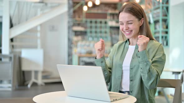 Excited Woman Celebrating Success on Laptop in Cafe 