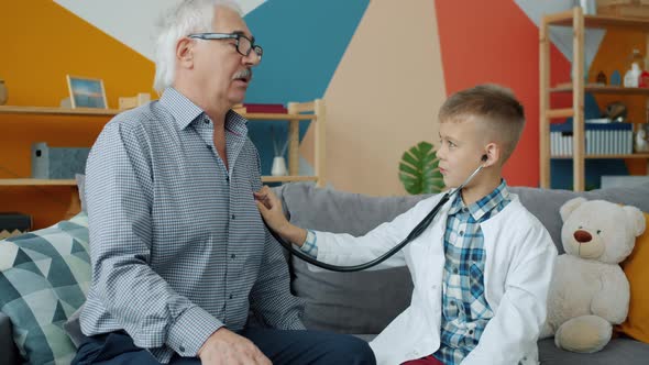 Adorable Child Playing with Grandfather Examining with Stethoscope in Apartment