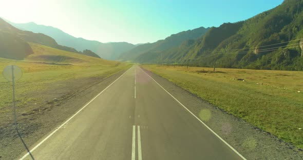 Aerial Low Air Flight Over Mountain Road and Meadow at Sunny Summer Morning