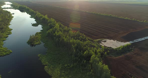 Natural Bog Lake and Forest Versus Peat Harvesting Production Field Aerial View