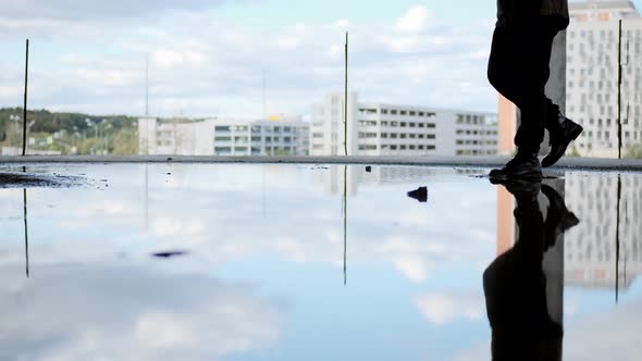 Unrecognizable Man or Woman Fighter Survivor Walks Through Puddle in Black Military Boots in