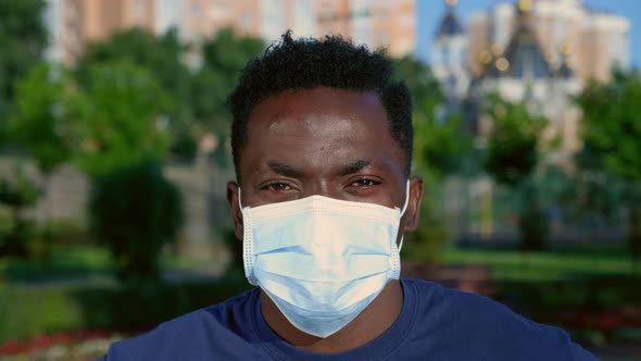 Close Up AfroAmerican Man Adult in Protective Medical Face Mask Looks Camera