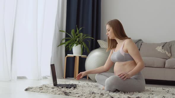Pregnant Woman in Sportswear at Home in the Living Room Doing Exercise for Video Lessons with a