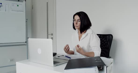 Female Teacher in Glasses Chatting on a Laptop During Remote Learning in Office