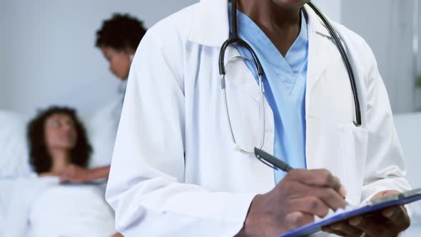 Close-up of African american doctor looking at camera while writing on clipboard in the ward 4k