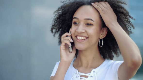 Close Up of Young Cheerful African American Woman Walking, Briskly Talking on Phone in Front Big