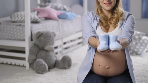 Pregnant Woman Showing Baby Booties To Camera