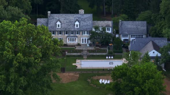 Pullback reveal of beautiful stone estate on private country club land. Large mansion with pool surr