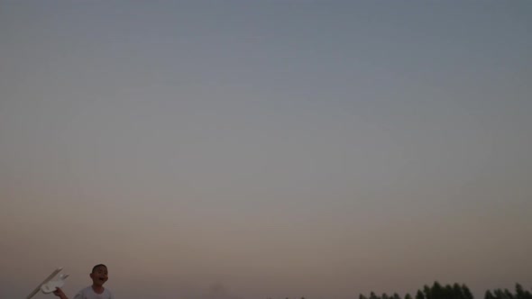 Boy playing wood airplane in the hands of running on a field at sunset alt