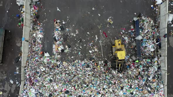 Aerial Shot of the Bulldozer Moving the Garbage and Trash in the Landfill Flattens It and Sorts It