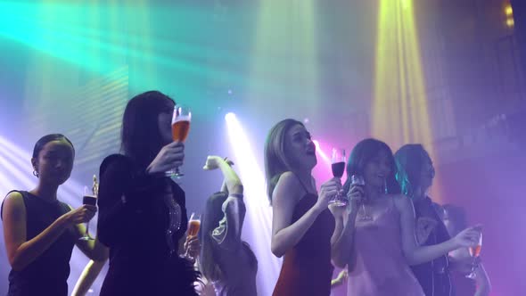 Group of People Dance in Disco Night Club to the Beat of Music From DJ on Stage