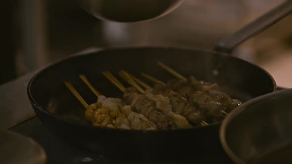 Hand of Chef Professional Pouring Cooking Meat with Soy Sause Using Brush Lrrl. Beef Pork on Stick