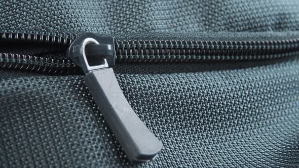 Hand closes the zipper lock of a green textile bag