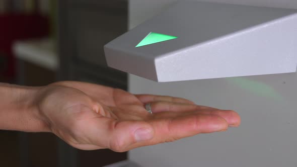 Automatic Touchless Hand Sanitizer Dispenser with Antiseptic in Use During COVID-19 Pandemic